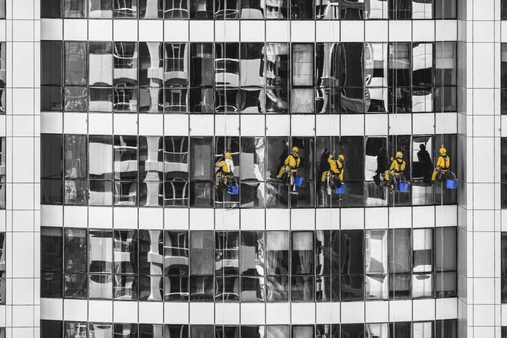 Yellow-suited window cleaners scale a high-rise building